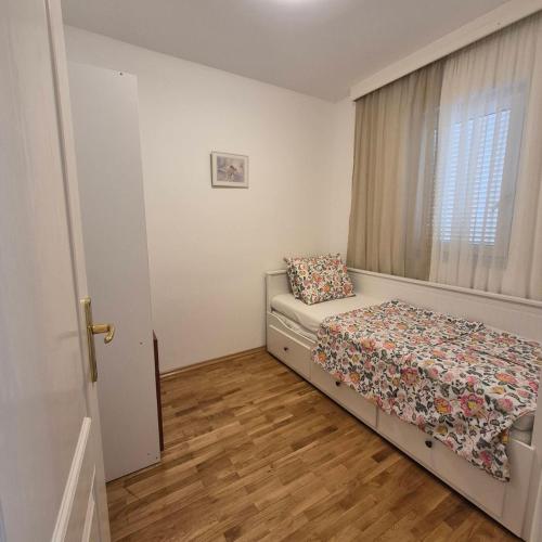 a small bedroom with a bed and a window at Bright & Spacious Apartment Budva in Budva