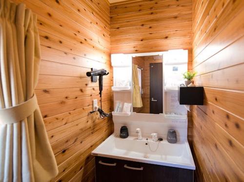a bathroom with a sink and a wooden wall at Sea Sky 赤崎 in Yoron