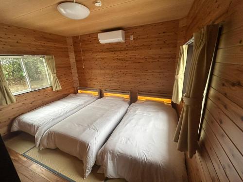 a bedroom with two beds in a log cabin at Sea Sky 赤崎 in Yoron