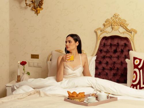 a bride sitting in bed drinking a glass of orange juice at Art Palace Suites & Spa in Casablanca