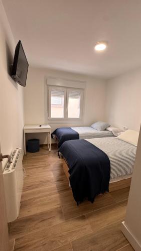 a bedroom with two beds and a television in it at AuraGalega Noro in Ribeira