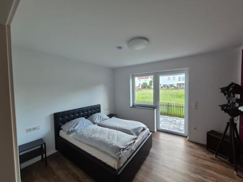 a bedroom with a bed and a large window at Ferienhaus "Pusteblume" - Entspannen in Weiterode in Bebra