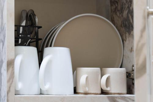 a shelf with white vases and a mirror at LUM Luxury Studios in Rethymno