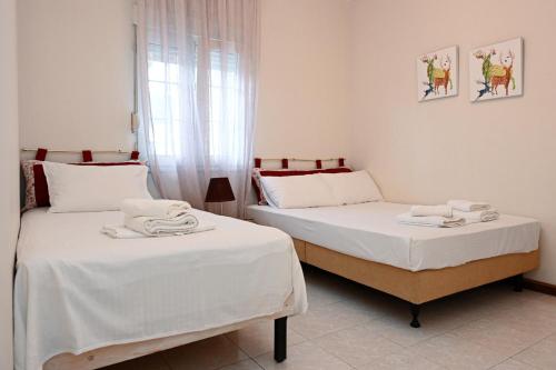 two beds in a room with white sheets at Sunrise Horizon in Iraklitsa