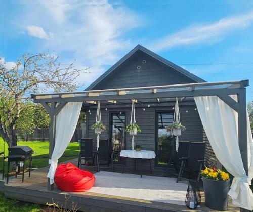 a gazebo with a table and white curtains at Kursīšu namiņš in Skulte