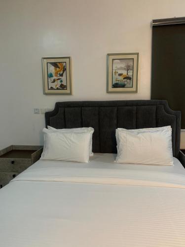 a bed with white sheets and two pillows at Beacon Shortlet in Kaduna