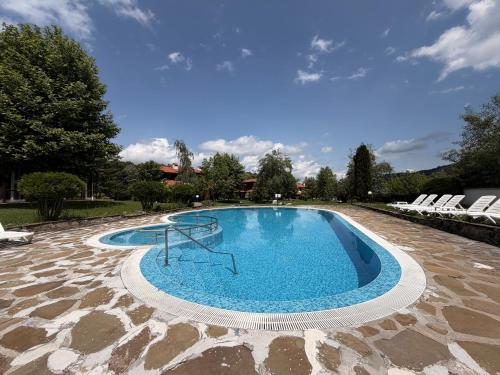 a large swimming pool with chairs around it at Марковската къща in Oreshak