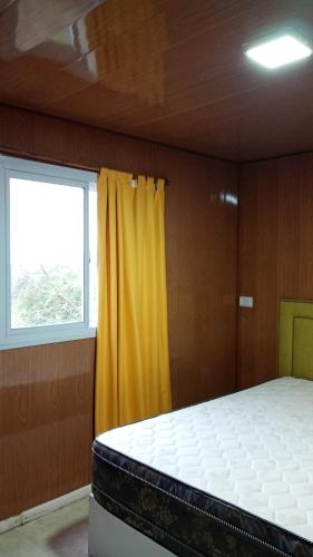 a bedroom with a bed and a yellow curtain at La Dominga Tiny House in La Granja