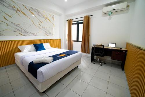 a bedroom with a bed and a desk with a computer at Behomy J-Home Bandung in Bandung