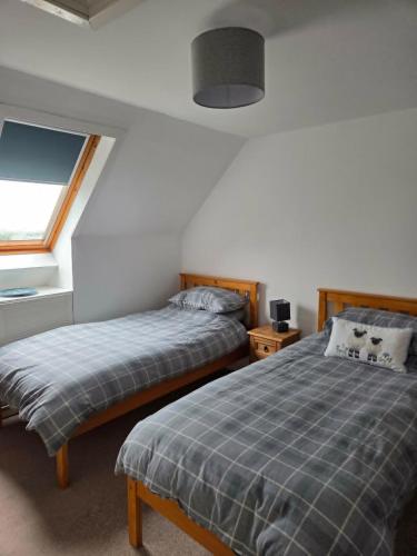 a bedroom with two beds and a window at The Smithy at 52 Vatisker in Stornoway