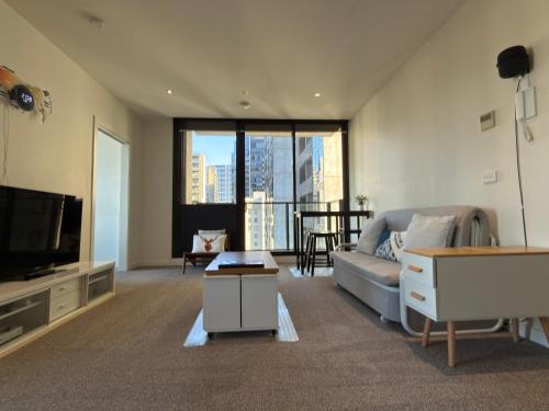a living room with a couch and a tv at Southbank Sanctum in Melbourne