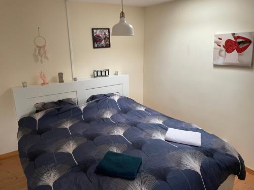 a bedroom with a bed with a blue comforter at Le Petit Perchoir à Aubusson in Aubusson