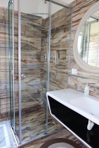 a bathroom with a shower with a sink and a mirror at Vila 26, Lura 2, Gjiri i Lalezit in Ishëm