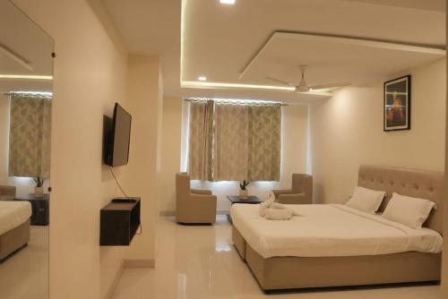 a hotel room with two beds and a television at Hotel Surya Teja Priime in Khammam