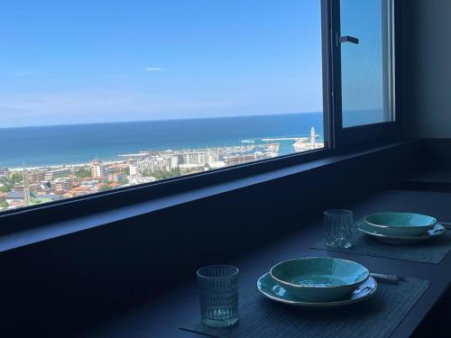 a table with two plates and glasses and a window at Suite 26 Rimini in Rimini