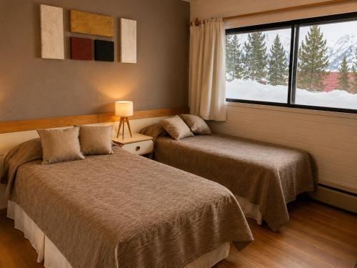 a bedroom with two beds and a large window at Departamento Boutique Las Leñas ATENAS in Las Lenas