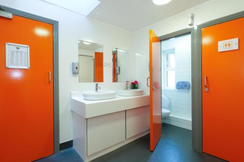 an orange bathroom with two sinks and a toilet at Galway City Hostel in Galway