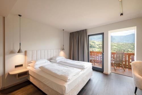 a bedroom with a large bed and a balcony at Hotel Öhlerhof in Lagundo