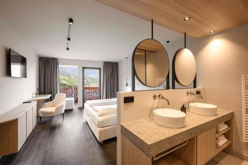 a bathroom with two sinks and a bedroom at Hotel Öhlerhof in Lagundo