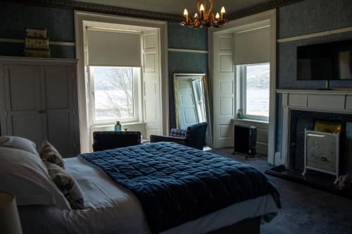 a bedroom with a bed and two windows and a fireplace at The Shore House in Lochgoilhead