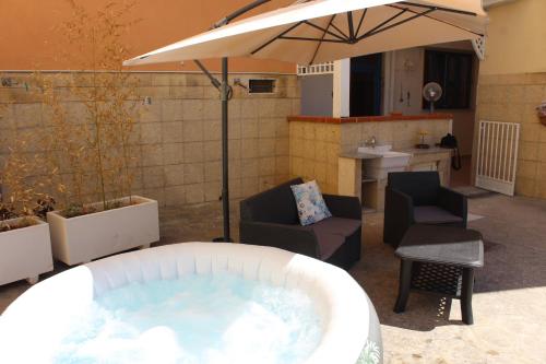 a hot tub with chairs and an umbrella on a patio at Casa Briseida in Baia Verde
