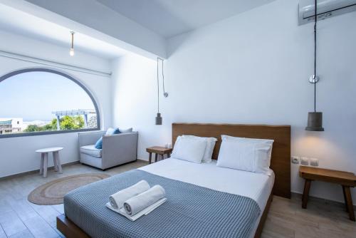 a bedroom with a bed and a chair and a window at Naxos Infinity Villa and Suites in Naxos Chora