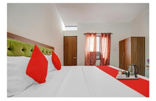 a bedroom with a large white bed with red pillows at Hotel R Himalayan in Mohali