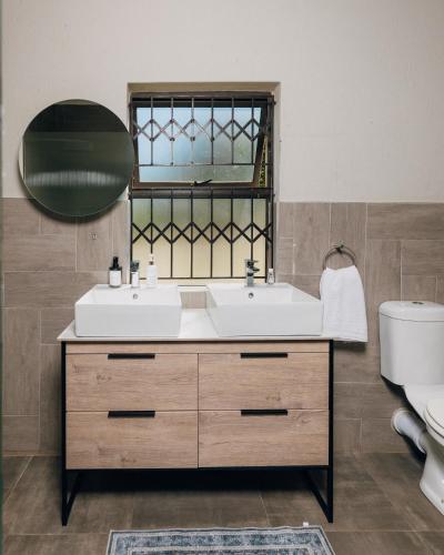 a bathroom with a sink and a mirror and a toilet at Emlanjeni Guest Lodge in White River