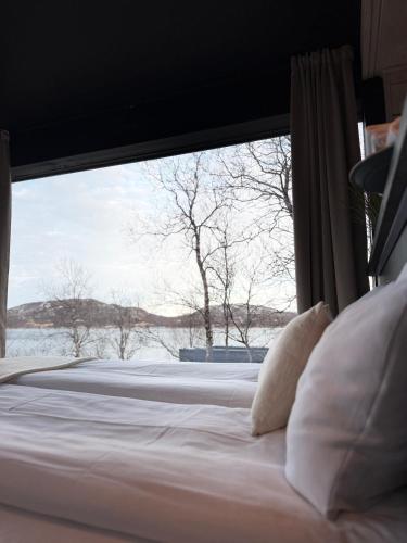 a bed with a large window in a bedroom at Aurora Sea Lodges in Karpbukt
