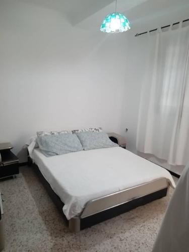 a bedroom with a white bed with a window at Résidence EPLF SAKET BÉJAÏA in Bejaïa