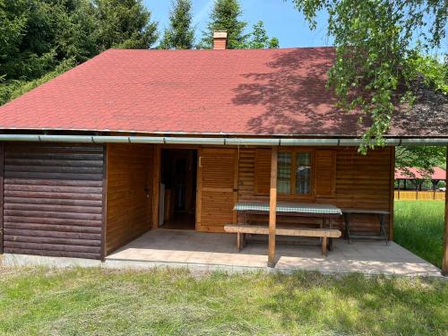 a wooden cabin with a bench and a red roof at Ivói Faház in Izvoare