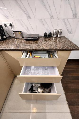 a kitchen counter with white drawers and a granite counter top at Glory Stays in Noida