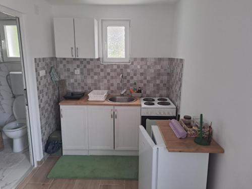 a small kitchen with white cabinets and a sink at Perucac Apartman in Perućac