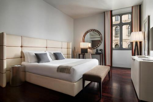 a bedroom with a large white bed and a mirror at Sina The Gray in Milan