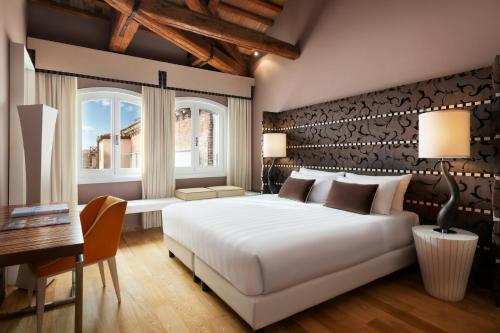 ein Schlafzimmer mit einem großen weißen Bett und einem Schreibtisch in der Unterkunft Sina Centurion Palace in Venedig