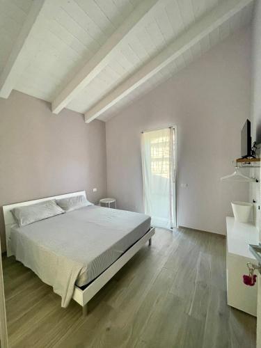 a white bedroom with a bed and a window at Villa Giovanna Rooms in Montelabbate