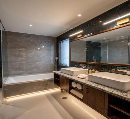 a bathroom with two sinks and a bath tub at Comfort Hotel Kishore Azamgarh in Āzamgarh