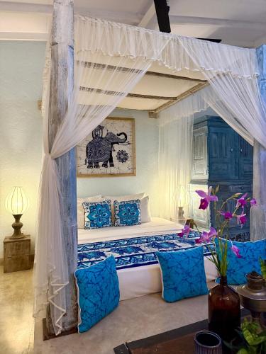 a bedroom with a canopy bed with blue pillows at GODDESS Kandy in Kandy