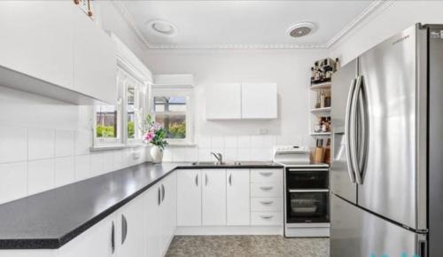 a white kitchen with white cabinets and a refrigerator at Timber and Tide in Saint Leonards
