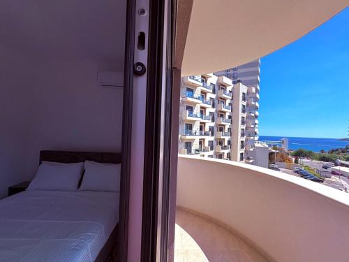 a bed on a balcony with a view of a building at Luxury 2BR Sea View & Garage & Twin Towers Becici in Bečići