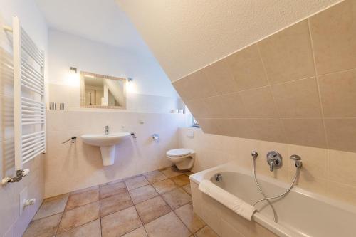 a bathroom with a sink and a tub and a toilet at Haus Sonnenschein 2 in Ahrenshoop