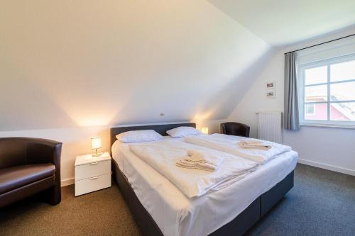 a bedroom with a bed with two chairs and a window at Haus Sonnenschein 2 in Ahrenshoop