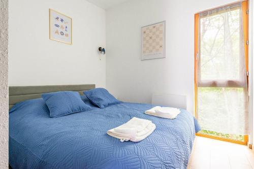 a bedroom with a blue bed with towels on it at Les Charmes C15 - Le Val Joly in Eppe-Sauvage