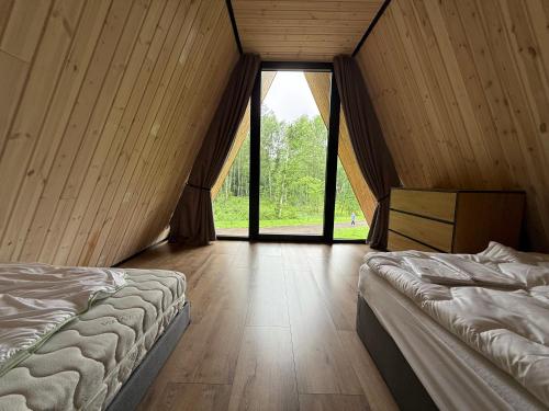 a bedroom with two beds and a large window at Frame Village in Žaugėdai