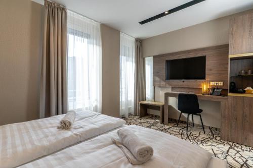 a bedroom with a bed and a desk and a television at Szatmári Hotel & Étterem in Jászberény