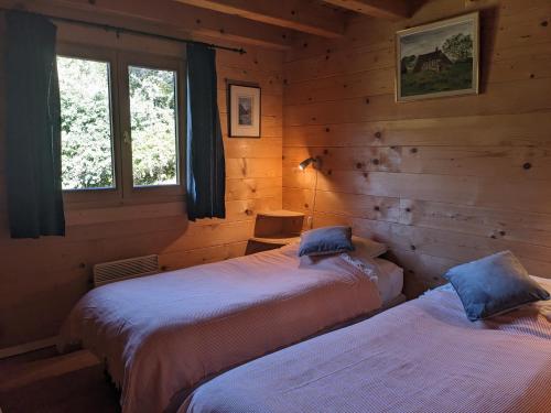 two beds in a log cabin with a window at Mountain Chalet in Beauvezer in Beauvezer
