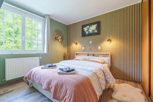 a bedroom with a bed with pink sheets and a window at La Jardinette - Avec jacuzzi privé in Futeau