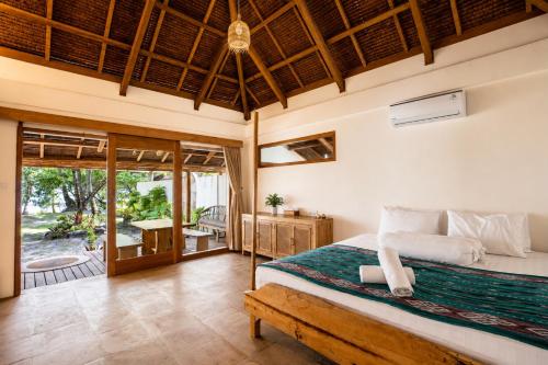 a bedroom with a large bed and a patio at Jala Villas Lances Right HTs Mentawai in Katiet