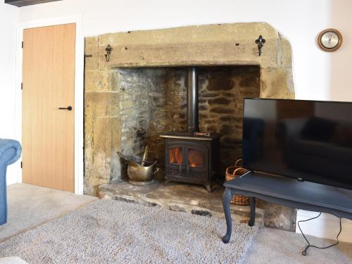 a stone fireplace with a stove in a living room at Causeway Cottage in Wolsingham