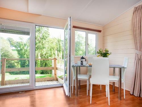 a dining room with a table and chairs and a balcony at 2 The Folly's - Uk45188 in Abbotskerswell